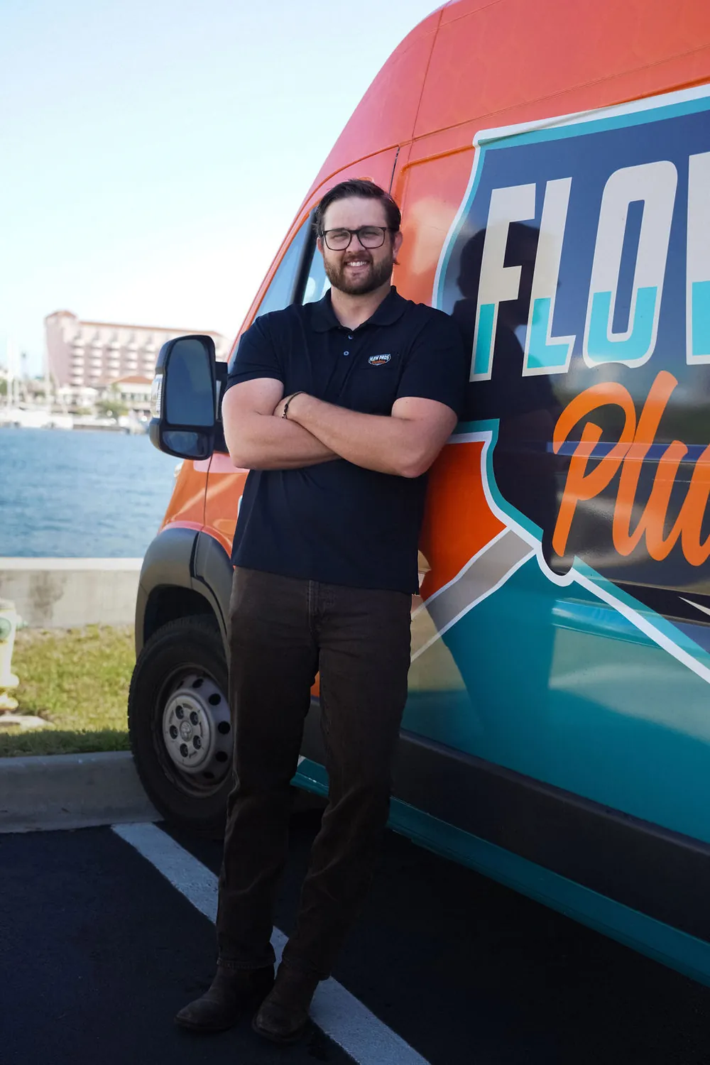 Jared, owner of Flow Pros Plumbing, leaning on the orange and teal Flow Pros van on the St. Petersburg waterfront