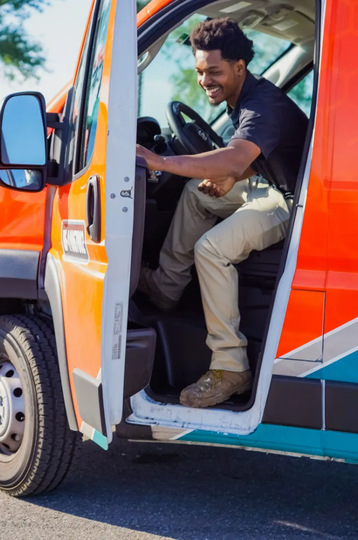 Smiling Flow Pros technician stepping out of the driver seat of the Flow Pros service van