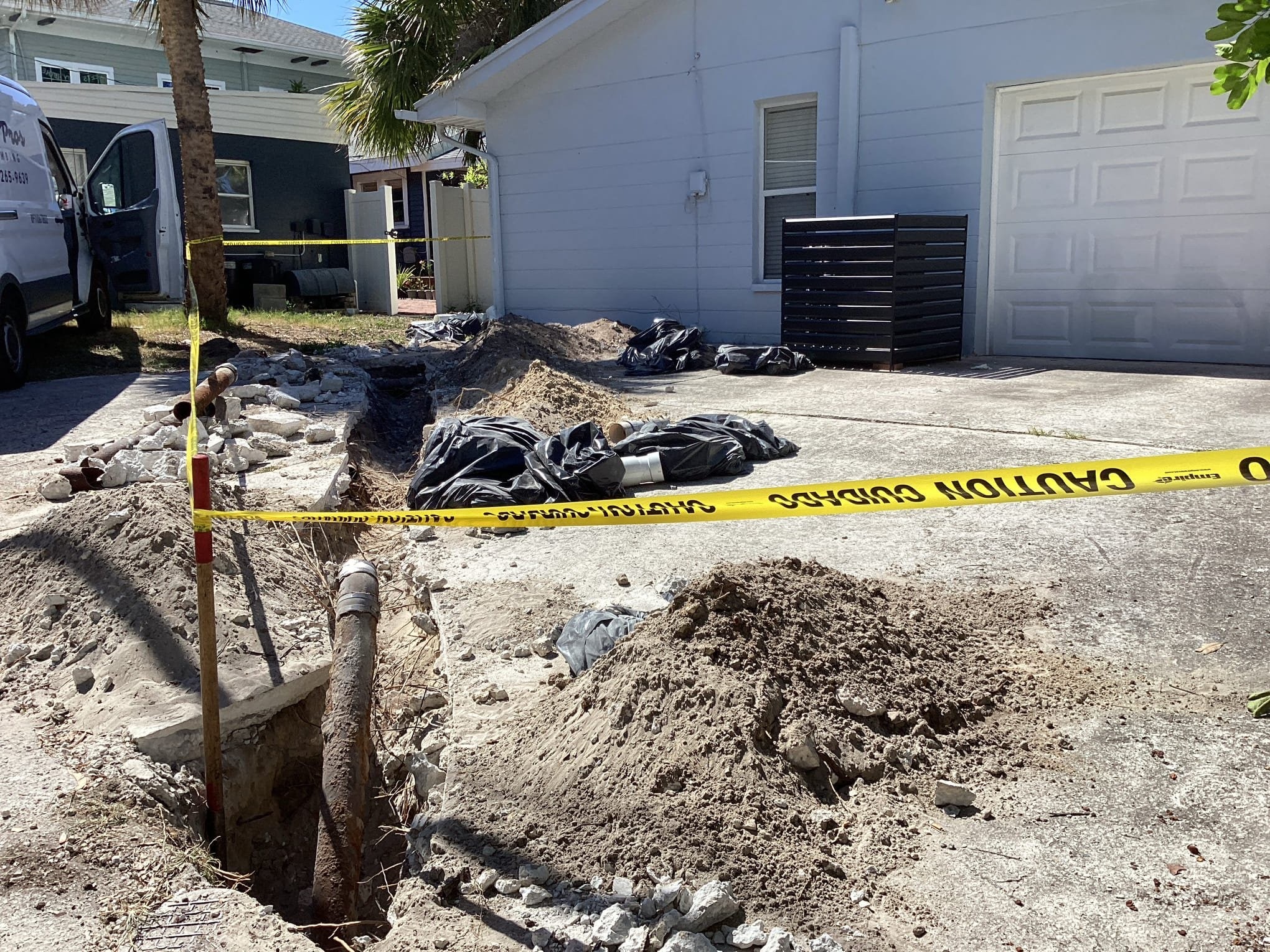 Flow Pros Plumbing van parked at a sewer lateral replacement job with new PVC pipe installed in a narrow side-yard trench