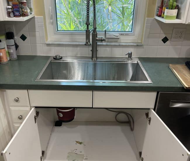 kitchen sink with cabinets open to check for hidden plumbing leak