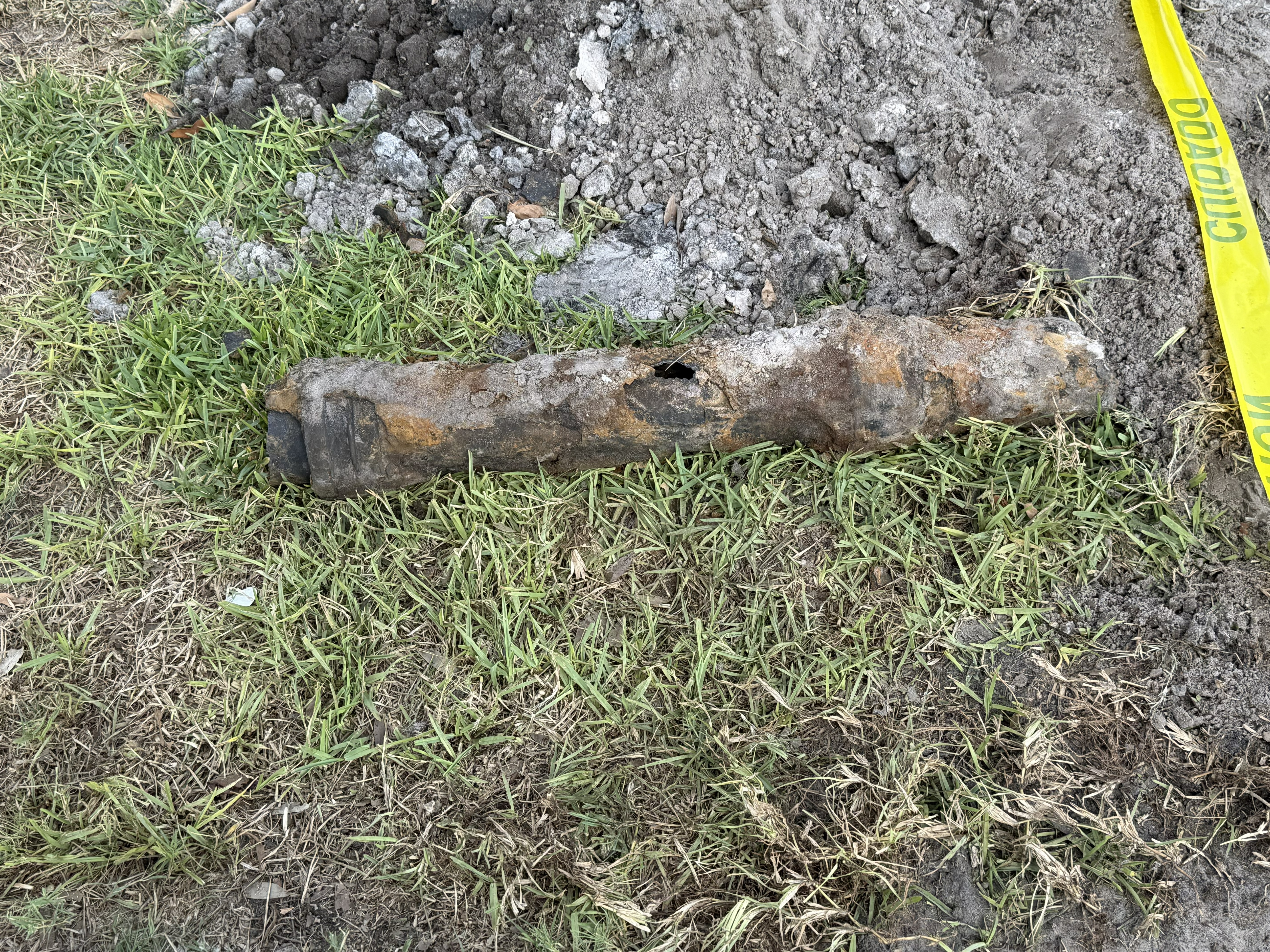 Flow Pros sewer lateral replacement in progress — excavated trench through a St. Petersburg driveway with old cast iron pipe removed and caution tape up